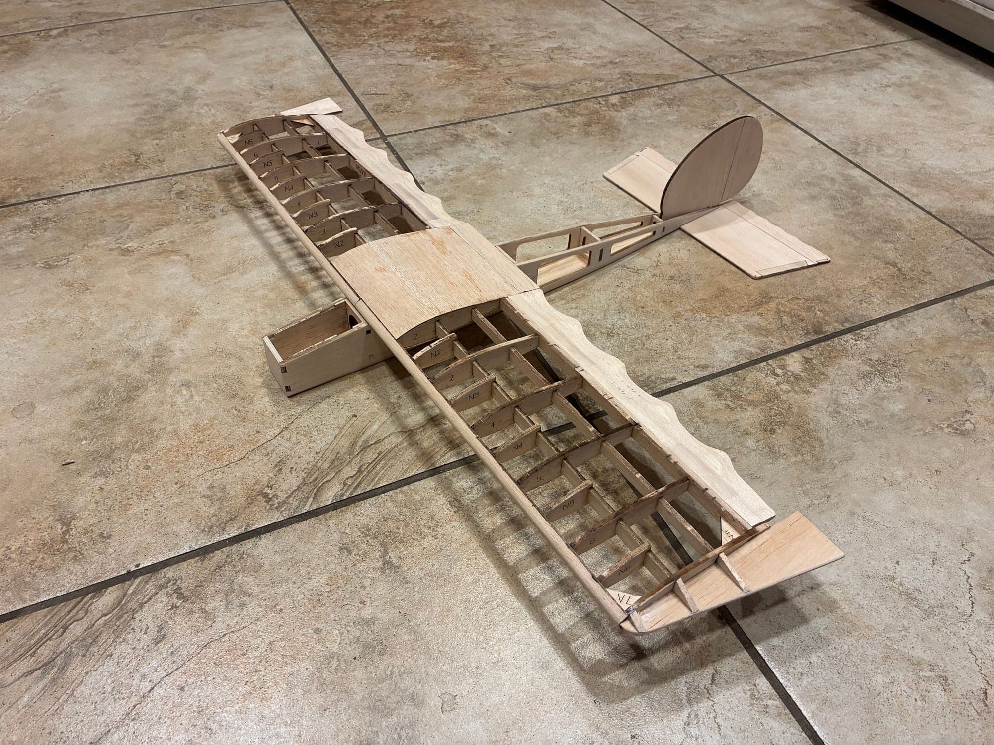 Fully assembled balsa airframe skeleton — wing, truss tail boom, fin, and stabilizer
