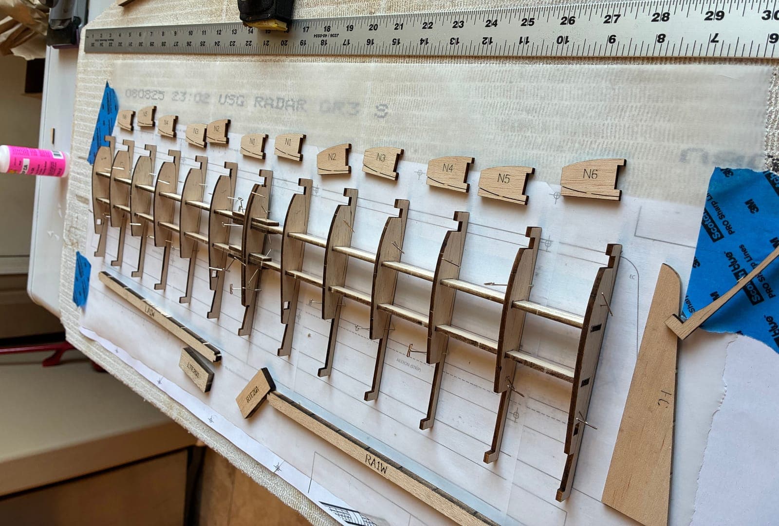 Rows of identical laser-cut ribs standing pinned on the building board