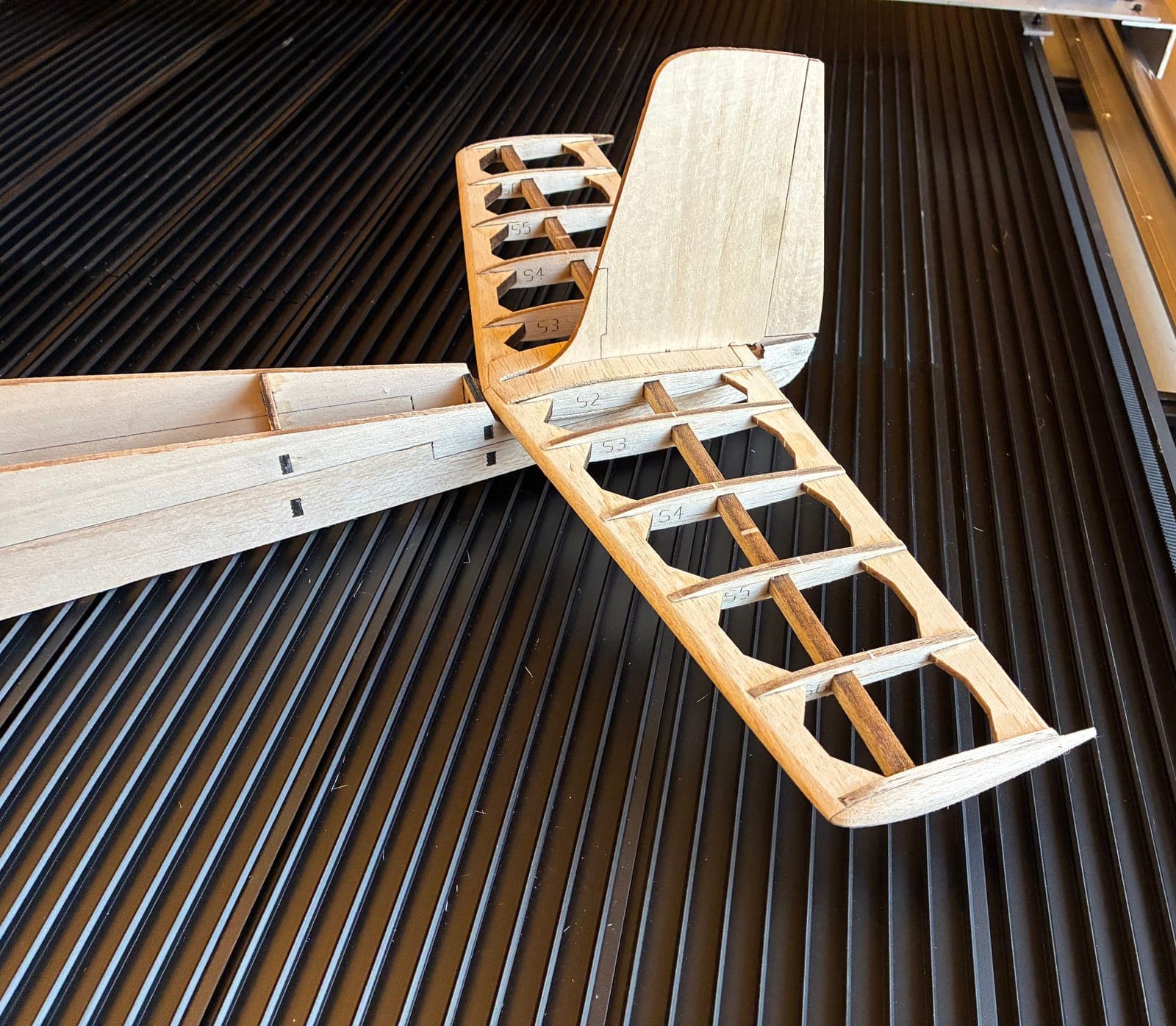 Bare balsa tail structure with laser-engraved part labels S2 through S6 visible on the ribs
