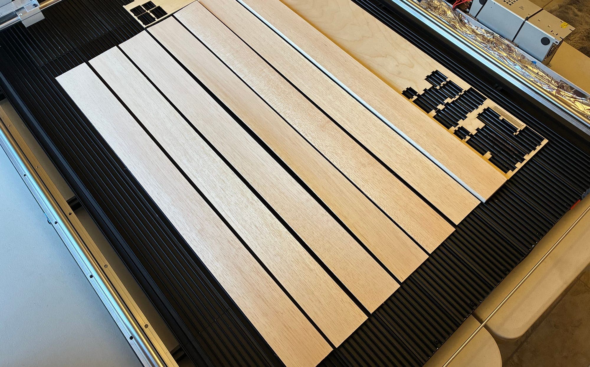 Laser bed loaded edge-to-edge with balsa sheet stock and a freshly cut plywood kit panel